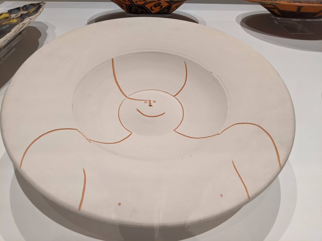 White plate with a simple orange-red line drawing of a smiling face character