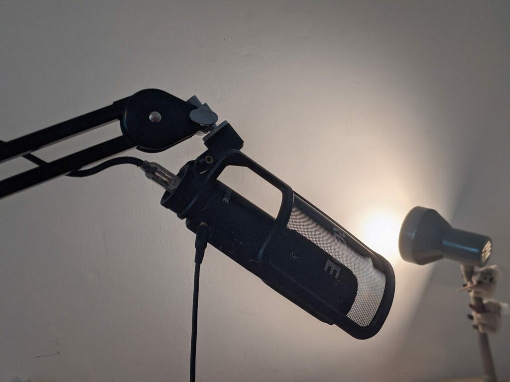 Professional microphone with boom arm against bright cloudy background