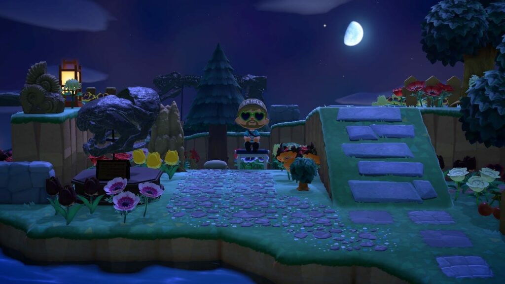 Nighttime scene of an illuminated playground or construction set with colorful structures, glowing pathways, and small figurines under a bright moon
