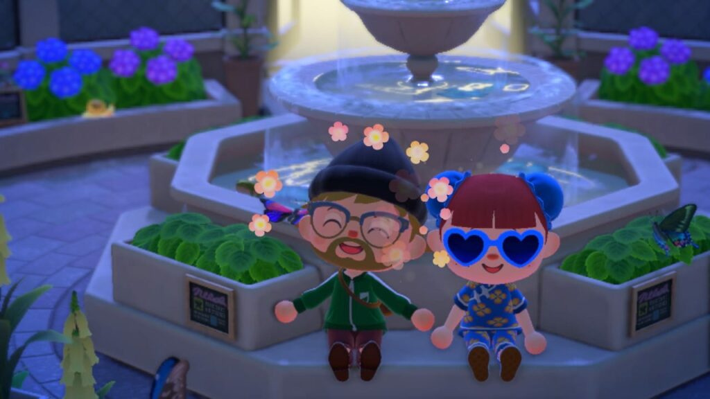 Two characters wearing heart-shaped sunglasses posing in front of a fountain with blue flowers and green planters