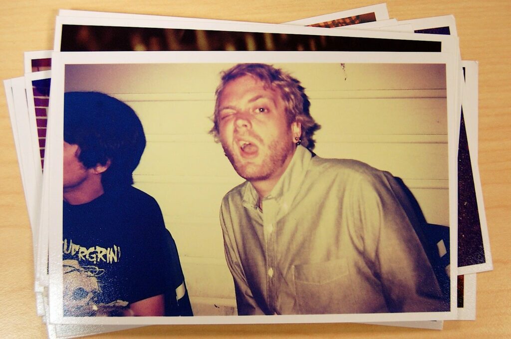 Vintage photograph slide showing two men, with one in the foreground wearing a light-colored shirt making an expressive facial expression