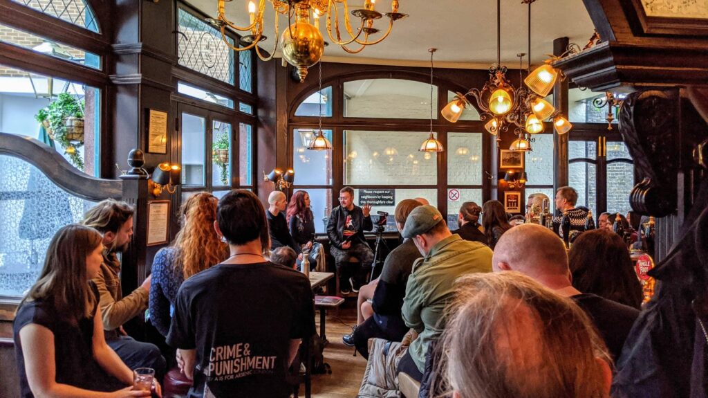 Group of people gathered inside venue with warm golden lighting and hanging brass fixtures