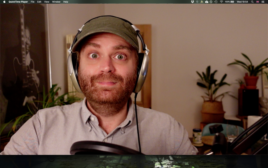 Screenshot: Person wearing headphones in QuickTime Player video recording with plants visible in background