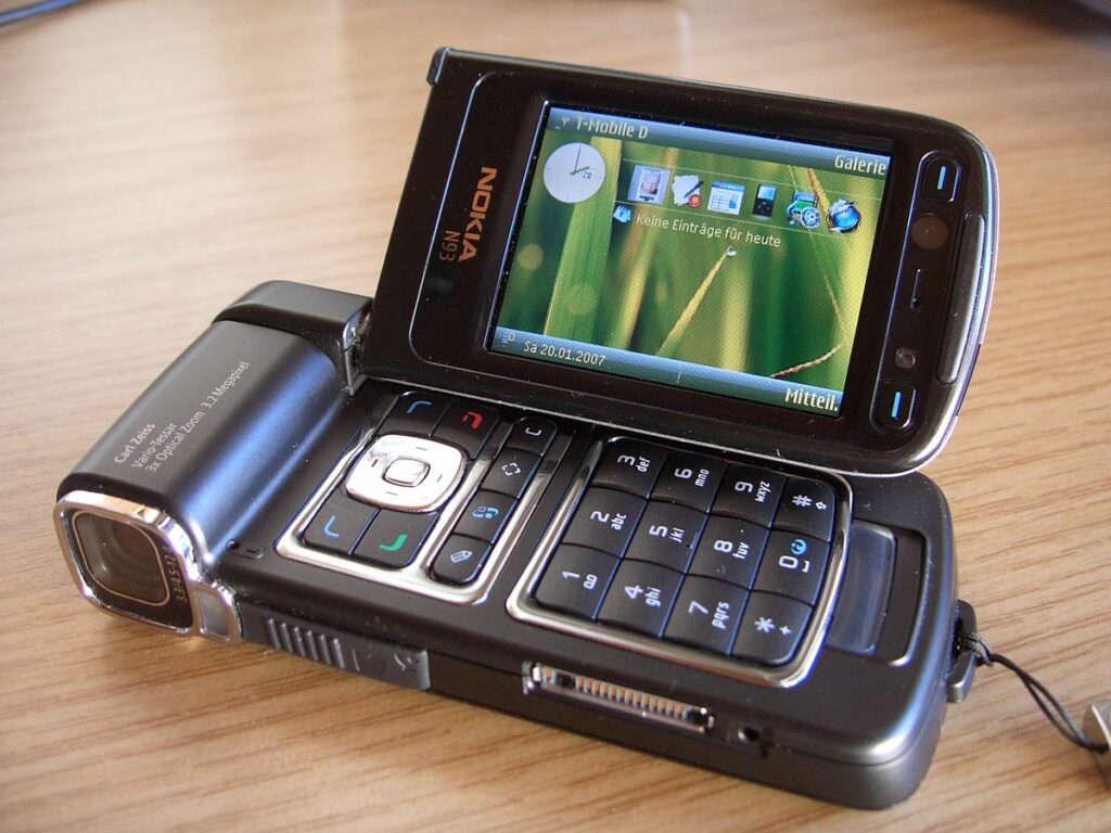 Nokia N93 mobile phone on wooden surface - black phone shown from side angle with screen displaying gallery menu
