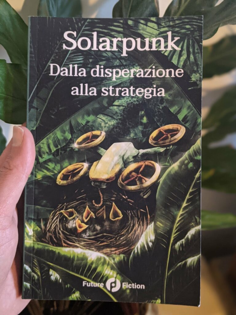 Photograph of Solarpunk book held in hand with green foliage background