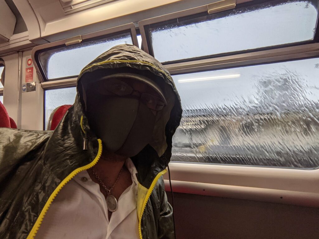 Person on train wearing black and yellow jacket looking out window at snowy landscape