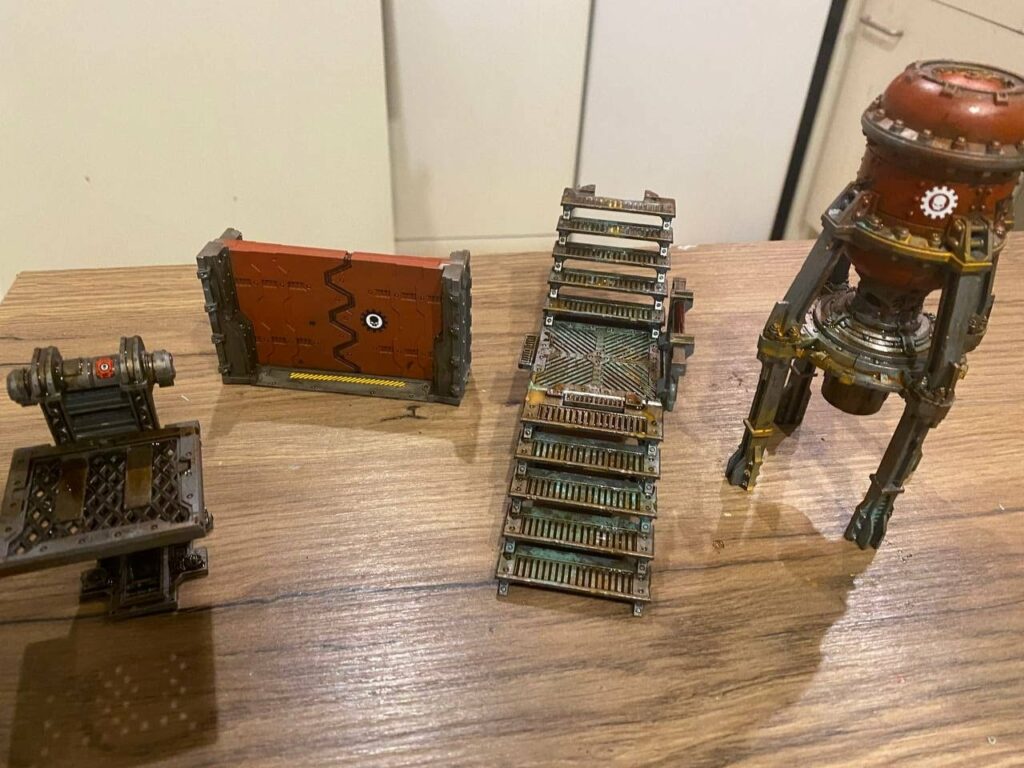 Warhammer 40K painted military vehicles including tank and transport on wooden surface