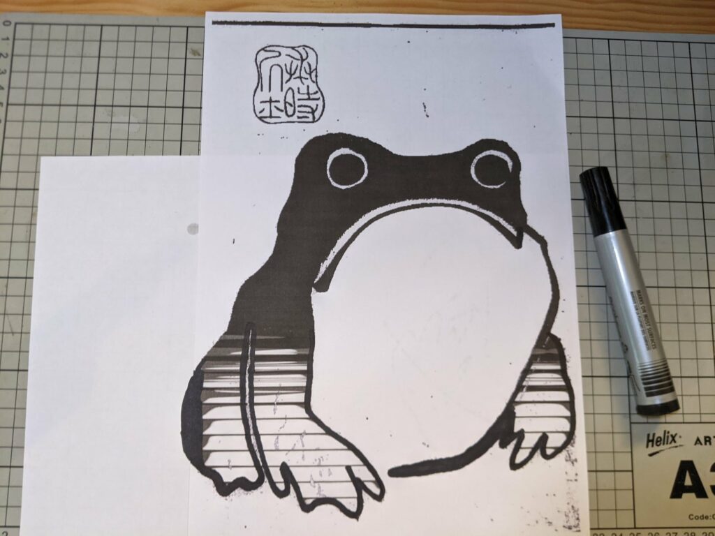Hand-drawn black ink illustration of frog on graph paper with marker nearby