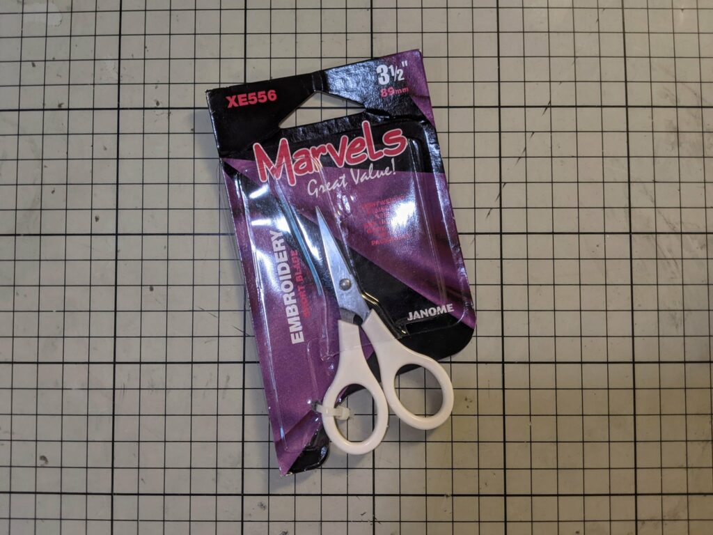 Janome Marvels embroidery machine kit package in purple and black with scissors on tiled background