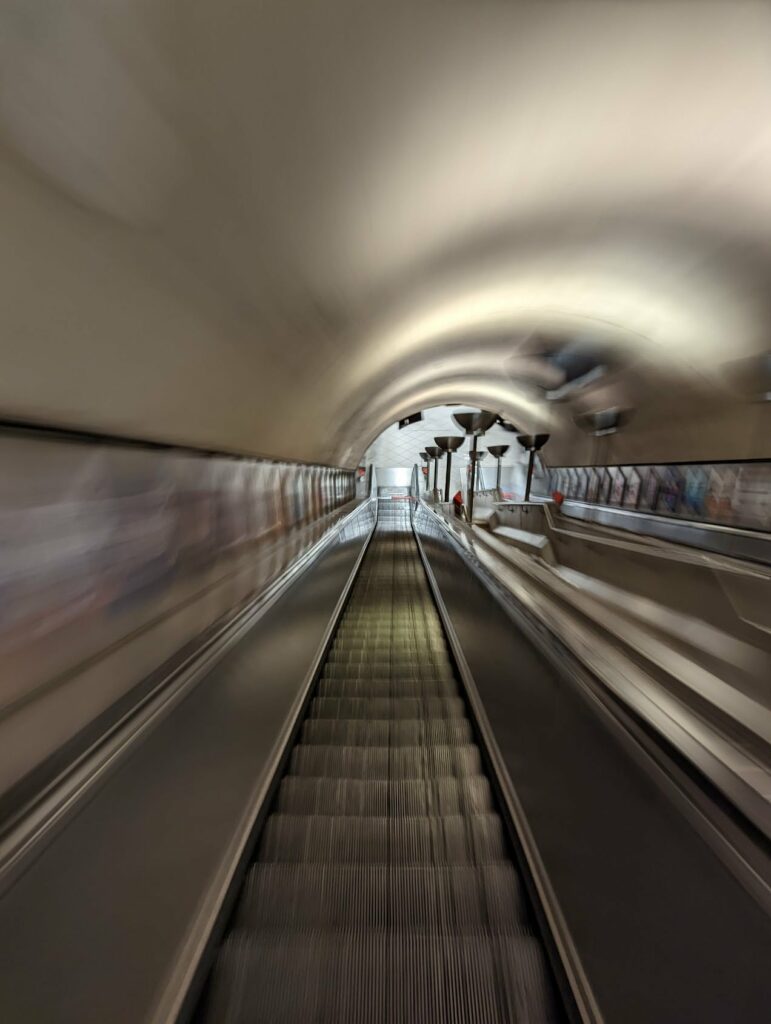 Motion blur photo of airport moving walkway with perspective lines leading to distant people