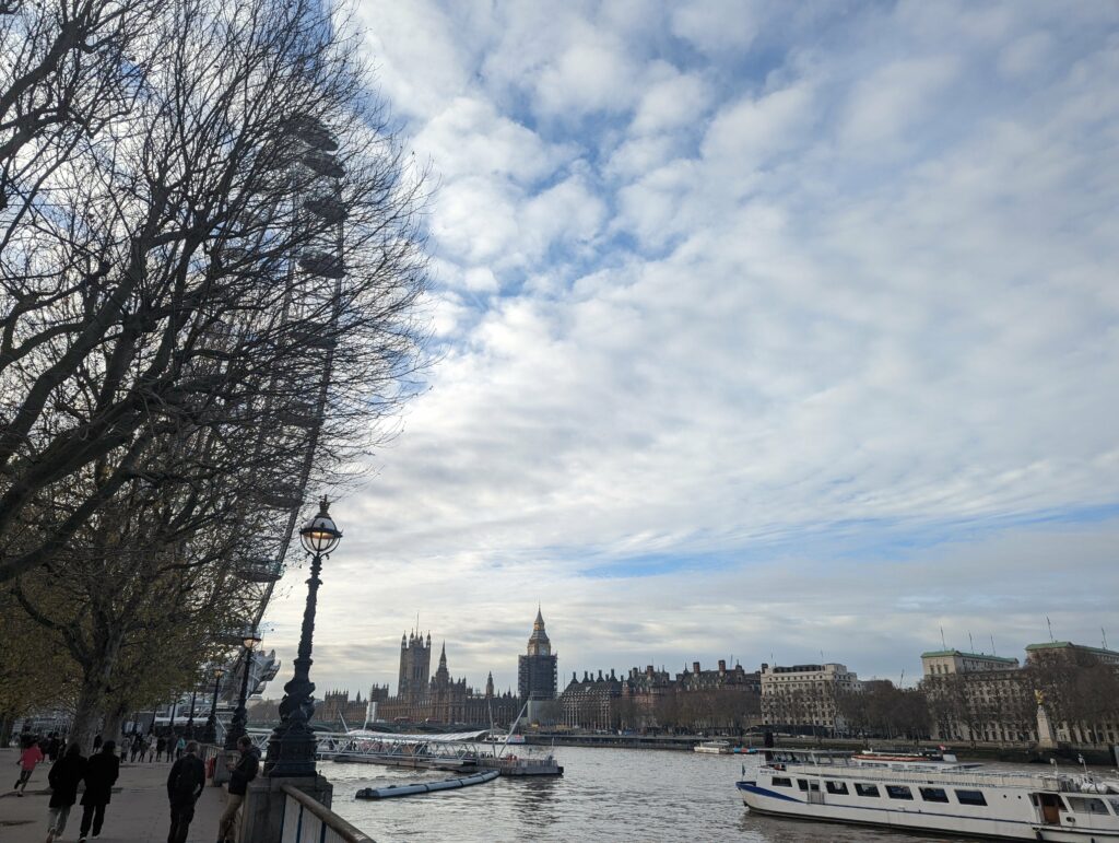London Thames river scene with Big Ben and Houses of Parliament, bare trees, street lamp, and tour boats