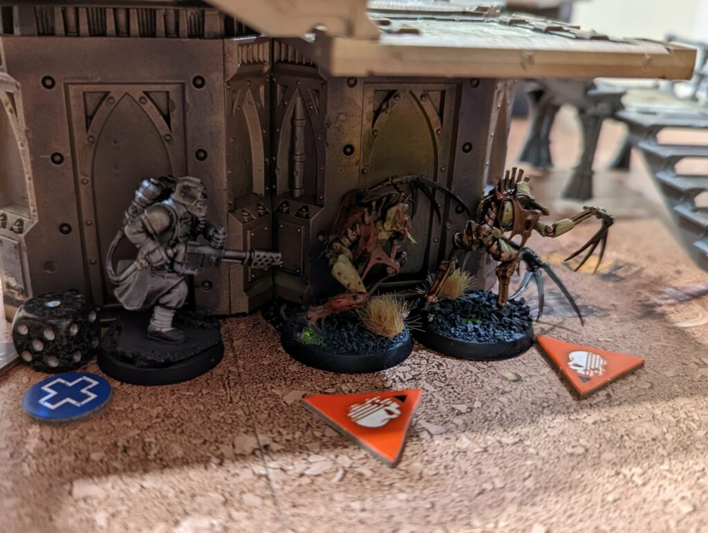 Warhammer 40K game board showing painted miniature Necrons and soldiers with gothic architecture terrain
