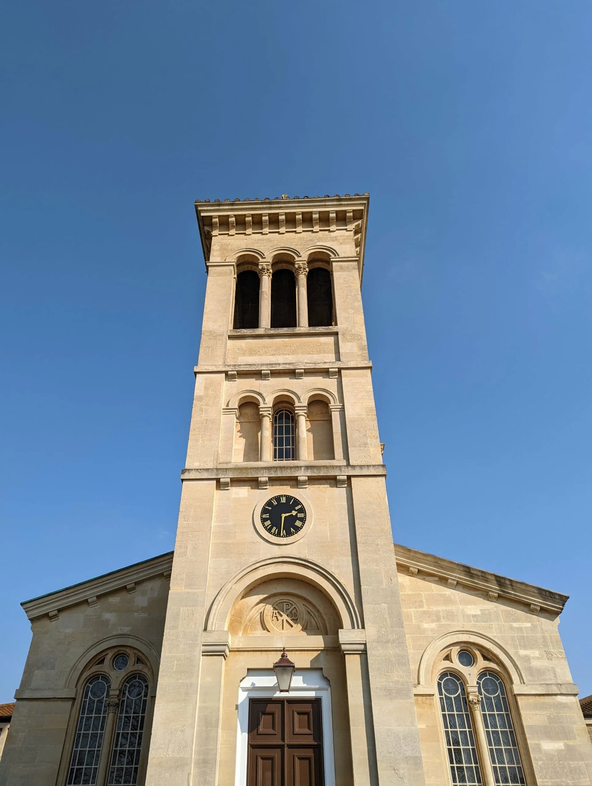 Stone church with clock tower and tall windows against blue sky
