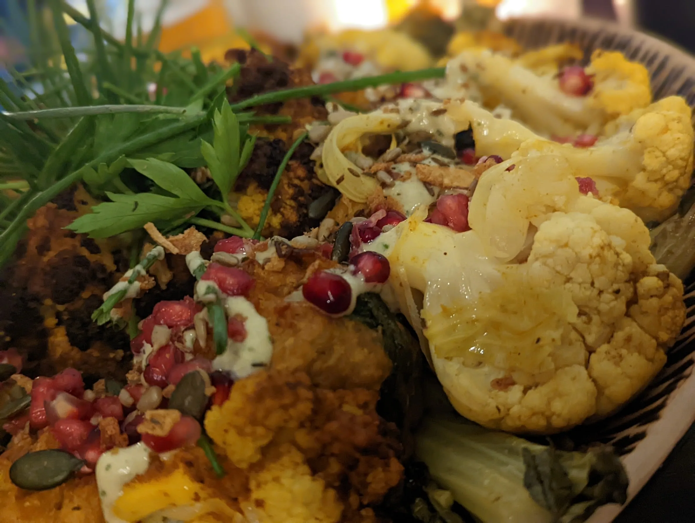 Food photography close-up of cooked cauliflower and roasted vegetables with herbs in serving bowl