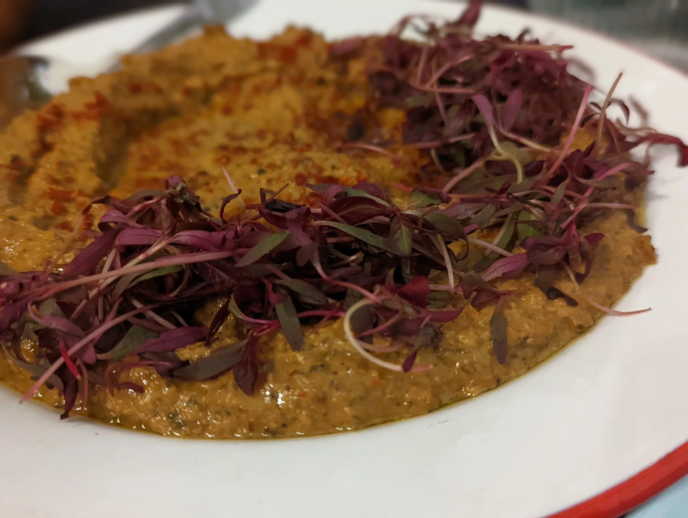 Curry dish with purple microgreens on white plate