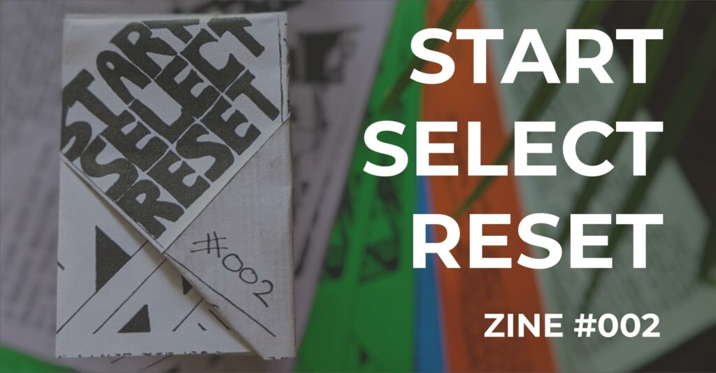 Featured image for Start Select Reset Zine #002 - A folded paper zine with bold black text and #002 handwritten on the corner.