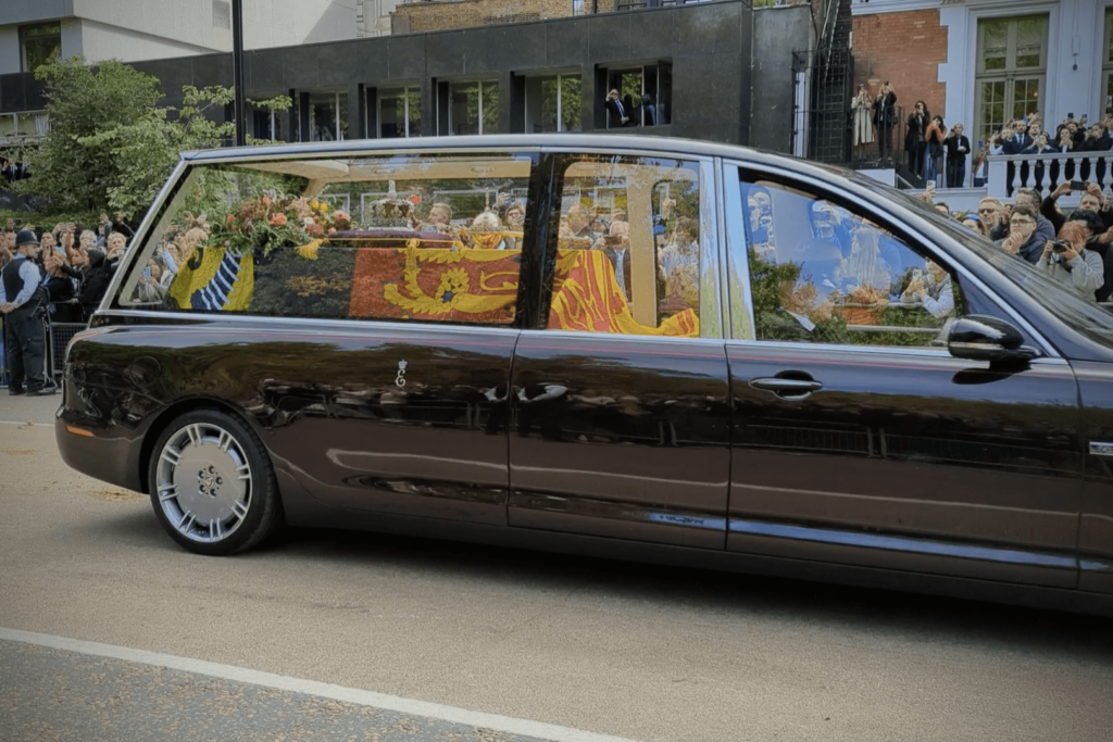Queen Elizabeth II's coffin draped in the Royal Standard inside the state hearse, passing crowds during the funeral procession in London.