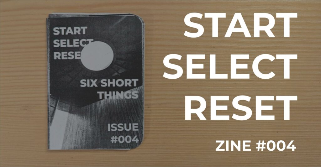 Featured image for Start Select Reset Zine #004 - a black and white zine on a wooden surface next to large white title text.
