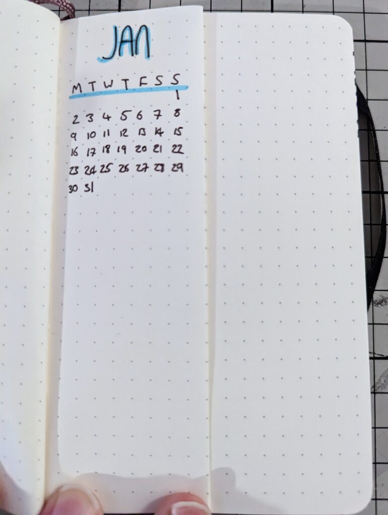 Hand-drawn January calendar in a dot grid notebook with blue highlights and handwritten dates.