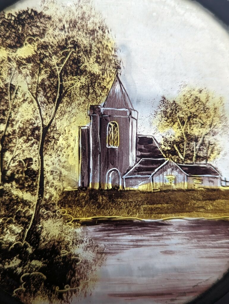 Sepia-toned glass slide illustration of a church with a pointed spire and trees beside a river.