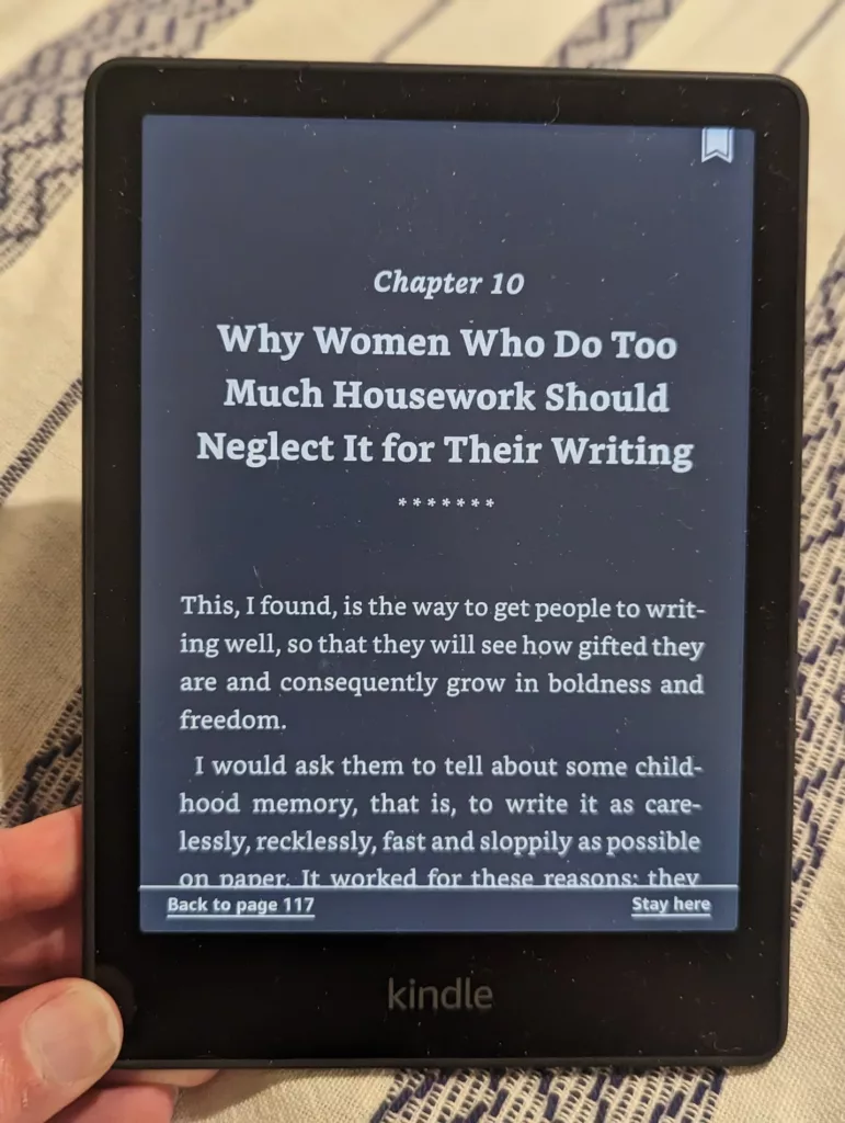 Kindle e-reader in dark mode displaying Chapter 10: Why Women Who Do Too Much Housework Should Neglect It for Their Writing.