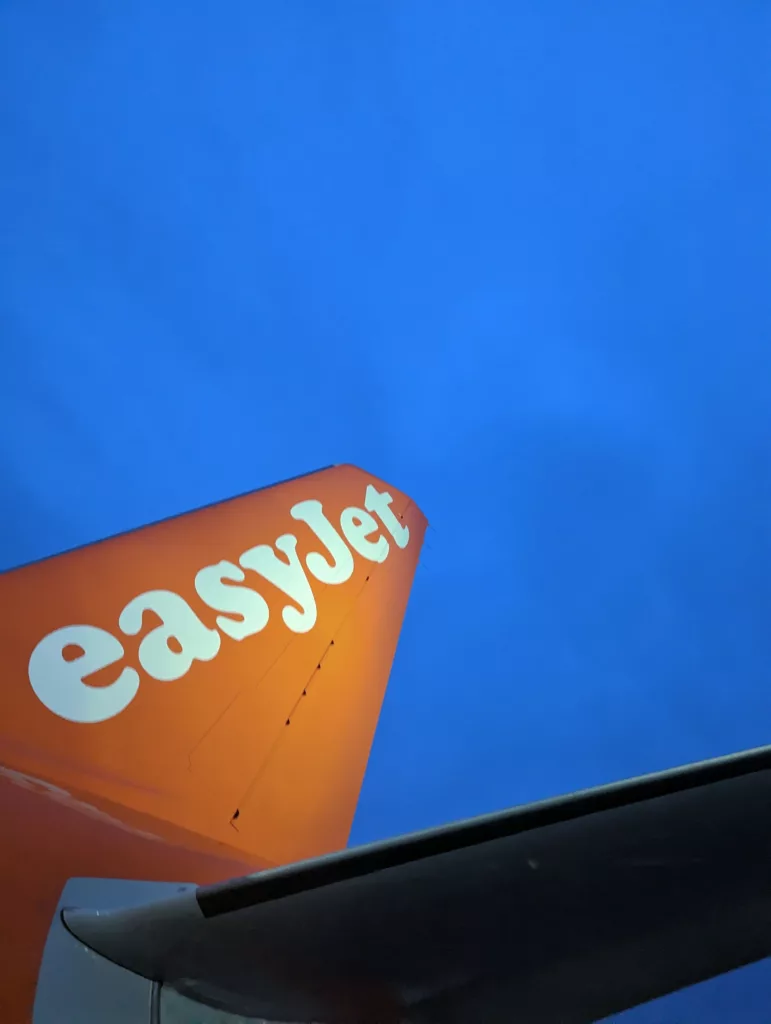 Orange easyJet aircraft tail fin with white logo against a deep blue sky.