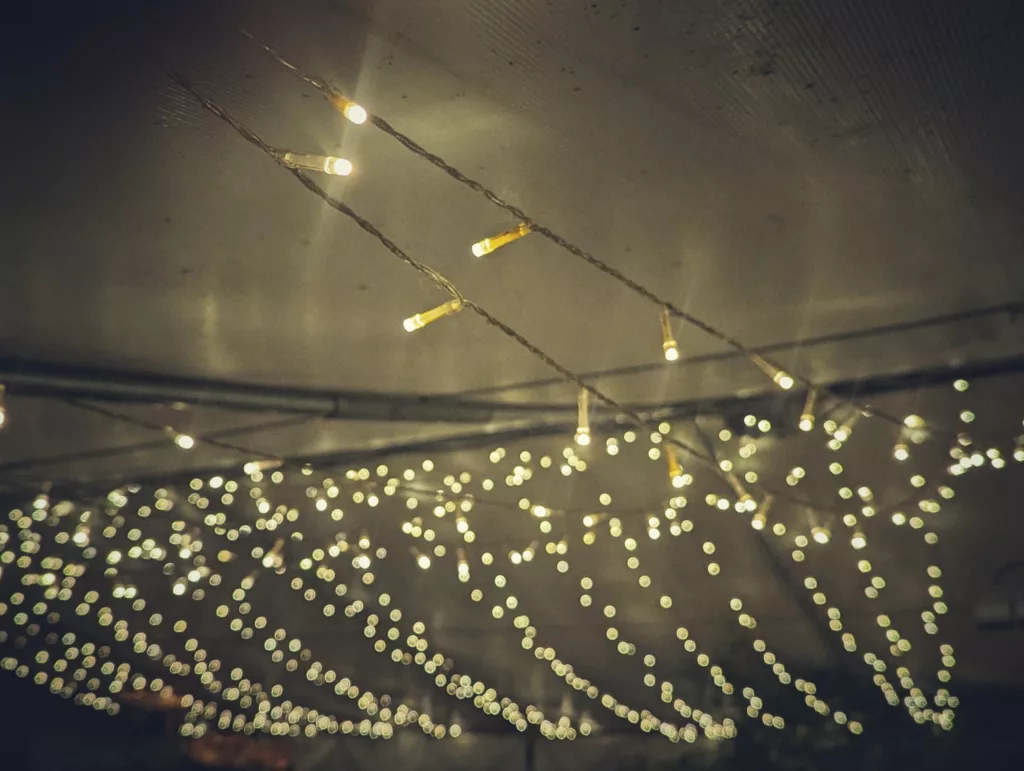Warm white fairy lights draped against a dark ceiling with soft, glowing bokeh circles in the background.