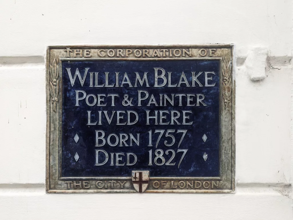 A blue commemorative plaque on a white wall for William Blake, poet and painter, stating he lived here from 1757 to 1827.