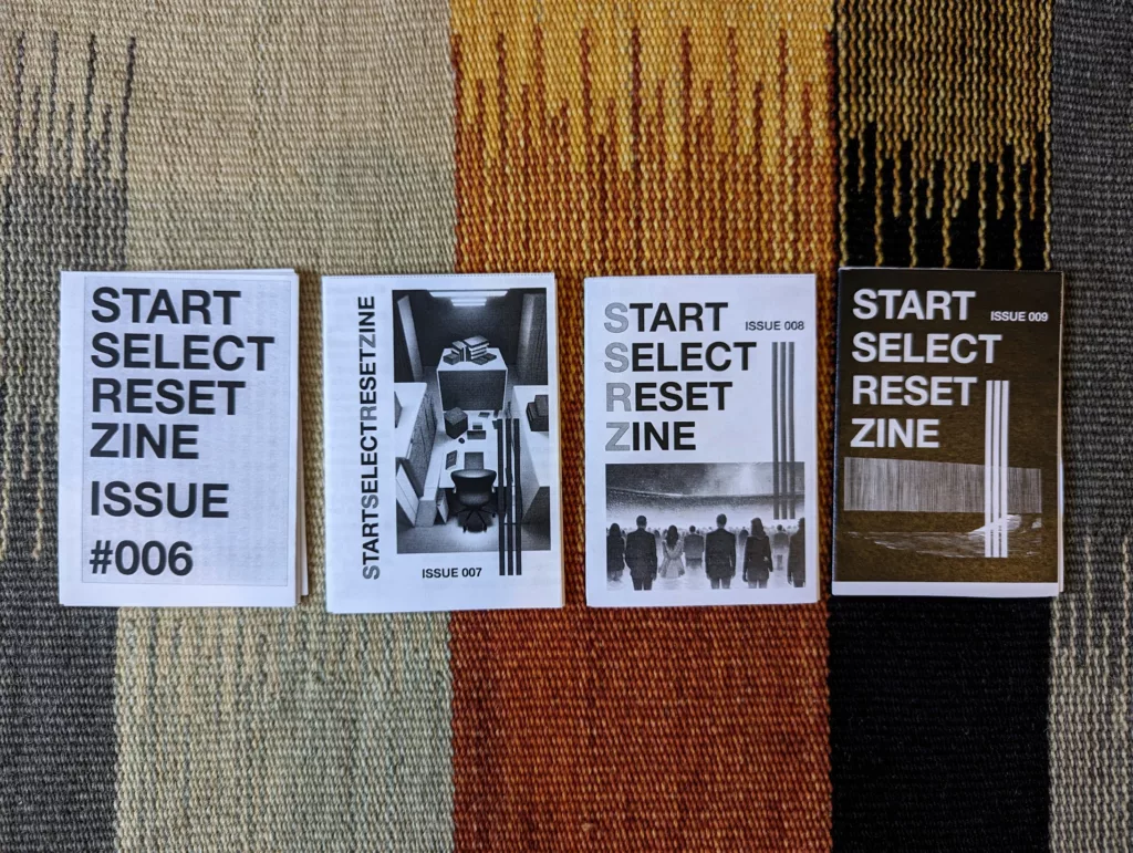 Issues 006 to 009 of Start Select Reset Zine arranged in a row on a vertically striped rug in shades of brown, orange, and grey.