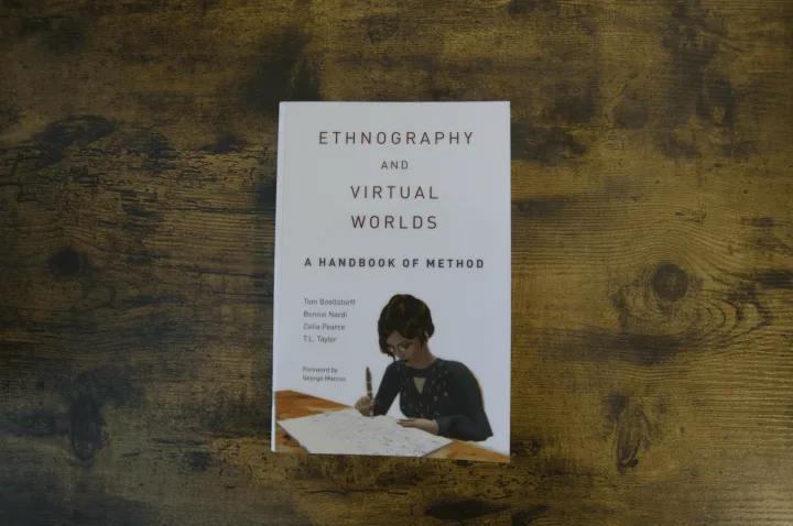 The book Ethnography and Virtual Worlds: A Handbook of Method lying flat on a dark, textured wooden surface.