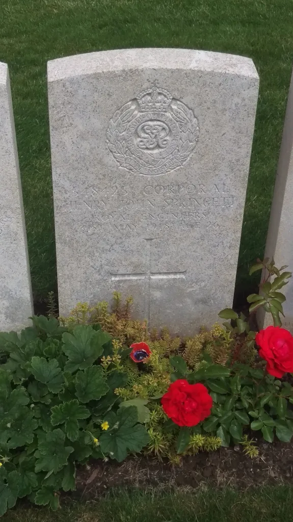 Headstone for Corporal Henry John Springett of the Royal Engineers, dated May 1918, with red roses and greenery at the base.
