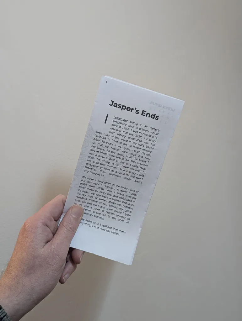 A hand holds a tall, narrow zine titled Jasper's Ends. The text describes a geography class in 1994 and the disappearance of the USSR from maps.