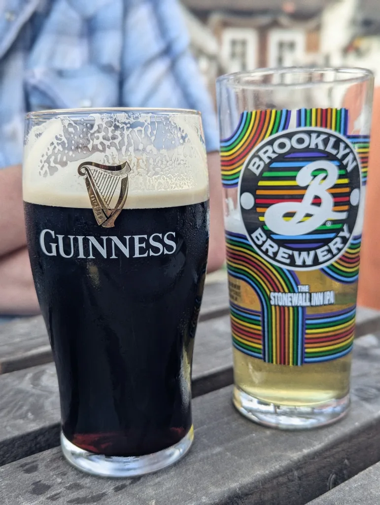 A pint of Guinness stout and a glass of Brooklyn Brewery The Stonewall Inn IPA on a weathered wooden table.