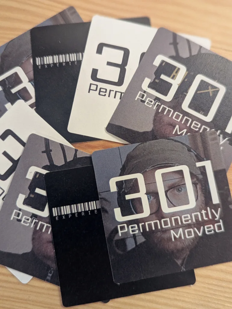 Several 301 Permanently Moved and experience.computer podcast stickers fanned out on a light wood tabletop.