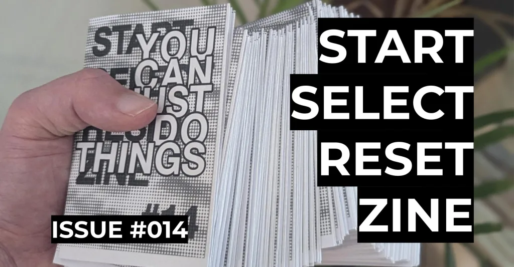 Featured image for Start Select Reset Zine Issue #014 - a hand holding a thick, fanned-out stack of small printed zines with black and white covers.
