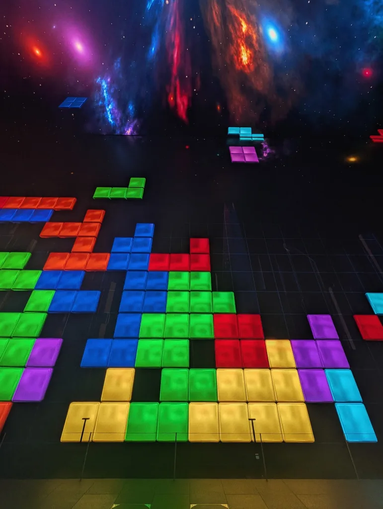 Tetris-shaped blocks and cosmic nebula displayed on a large LED wall in a dark room