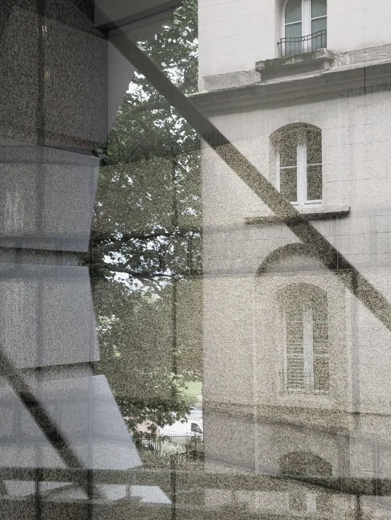 A layered reflection on a glass windowpane showing a classic stone building façade, arched windows, leafy green trees, and angular shadows.