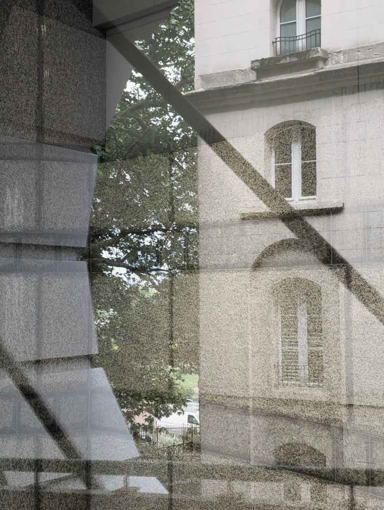 A layered reflection on a glass windowpane showing a classic stone building façade, arched windows, leafy green trees, and angular shadows.